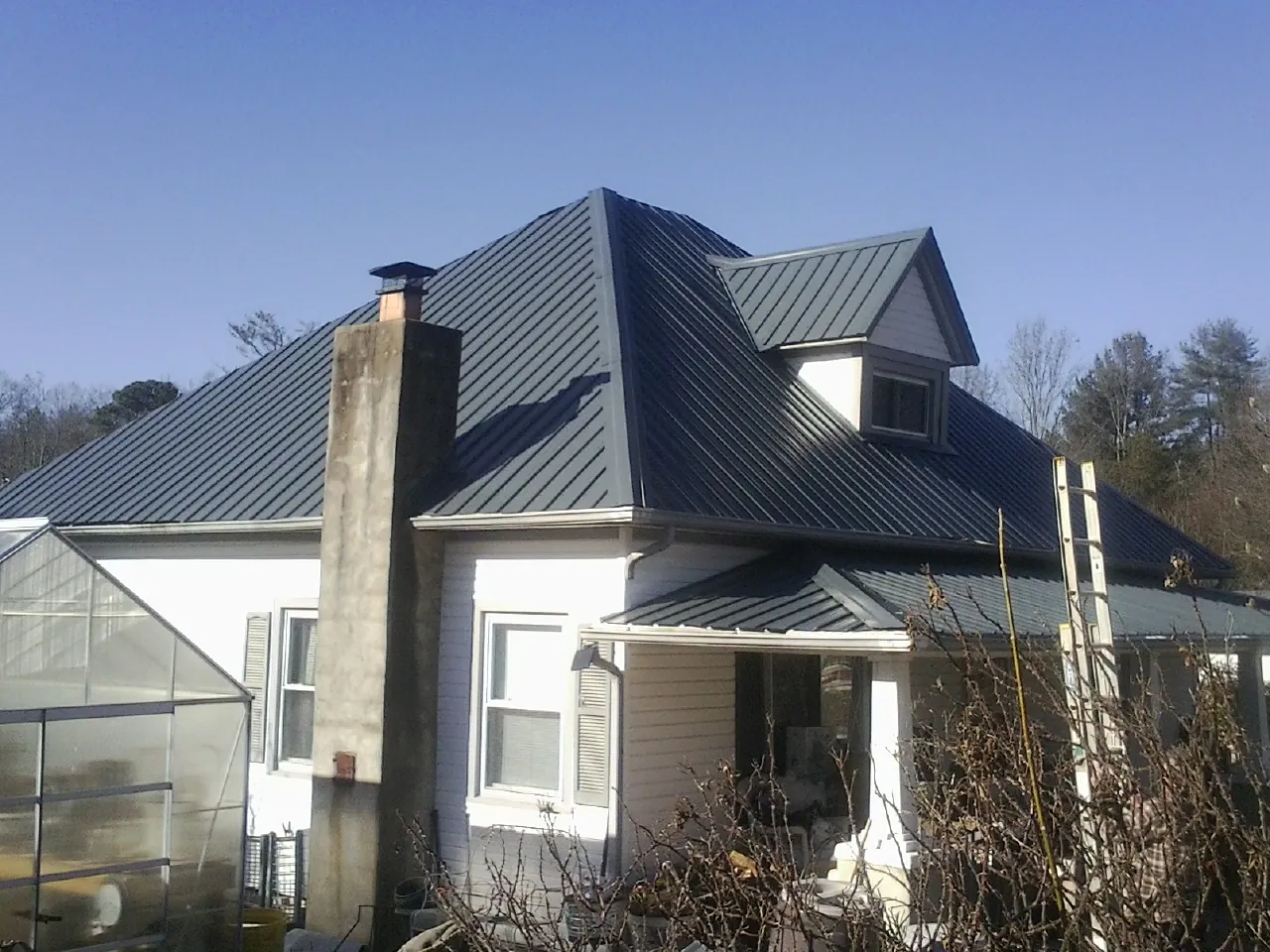 Dark blue standing seam metal roof on a white farmhouse with dormer — Slate & Tile Roof Repair by Roofing Brothers in Barwick