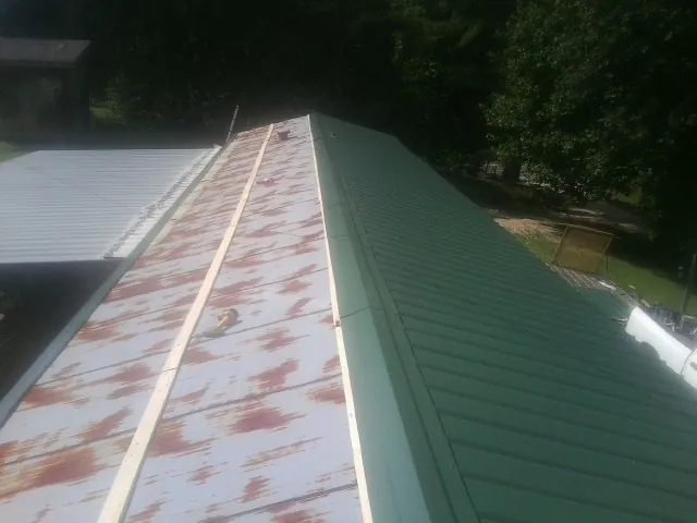 Old rusted panels beside newly installed green metal roofing — Wind Damage Roof Repair by Roofing Brothers in Barwick