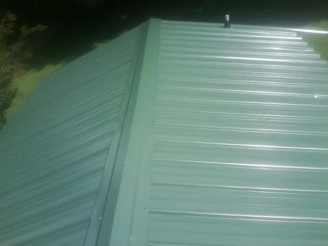 New green metal panels meeting at the ridge of a roof — Flat Roof Repair work by our crew in Barwick