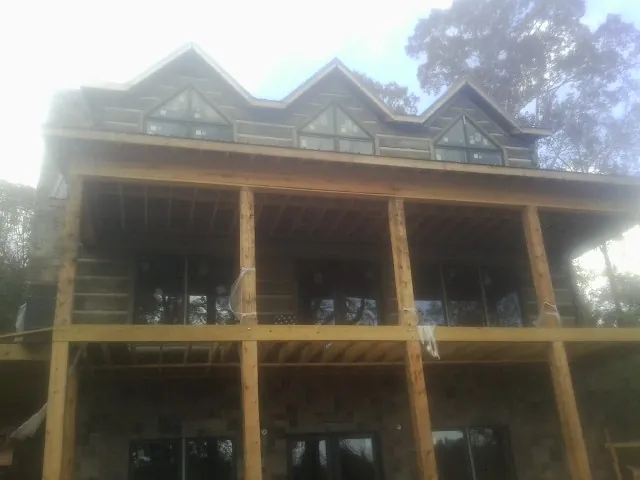 Dormers and porch framing on a large log home under construction — Roof Coating work by our crew in Barwick