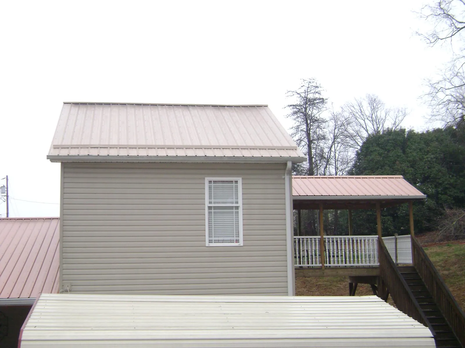Tan metal roofs on a two story addition and attached porch, from a Roof Replacement job in Barwick