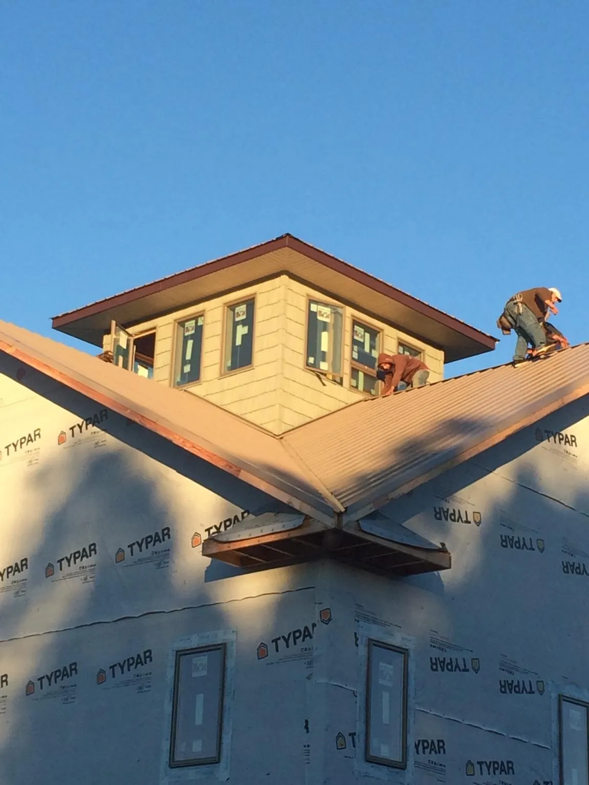 Roofers working around a rooftop cupola on a new metal roof at sunset — Roof Waterproofing in Barwick by Roofing Brothers